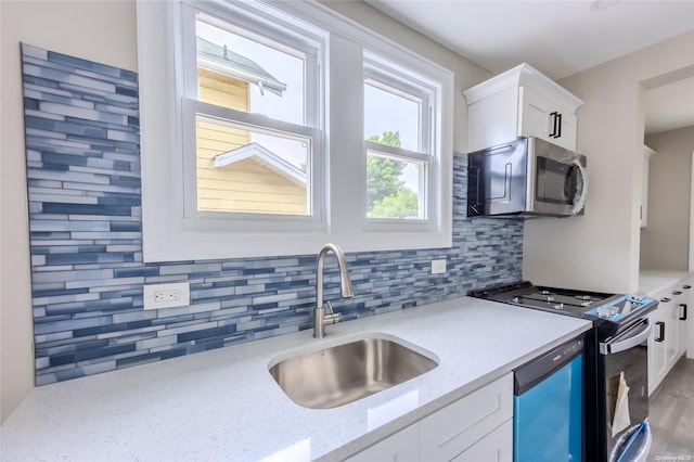 kitchen with sink, stainless steel appliances, light stone counters, decorative backsplash, and white cabinets