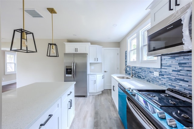 kitchen with stainless steel appliances, white cabinetry, and sink