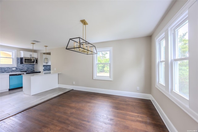 kitchen featuring appliances with stainless steel finishes, dark hardwood / wood-style floors, white cabinetry, and pendant lighting