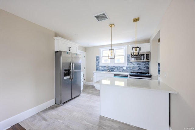 kitchen featuring kitchen peninsula, white cabinets, stainless steel appliances, and light wood-type flooring