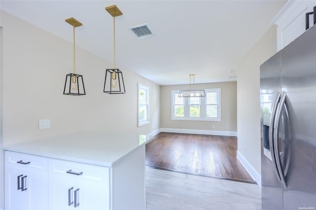 kitchen with decorative light fixtures, white cabinetry, light wood-type flooring, and stainless steel fridge with ice dispenser