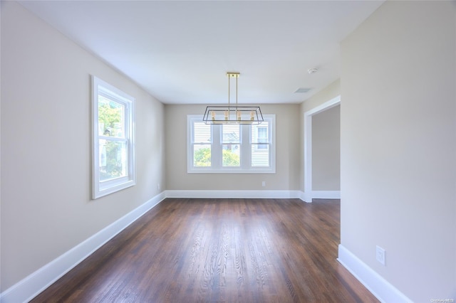 unfurnished dining area with dark hardwood / wood-style flooring and a chandelier