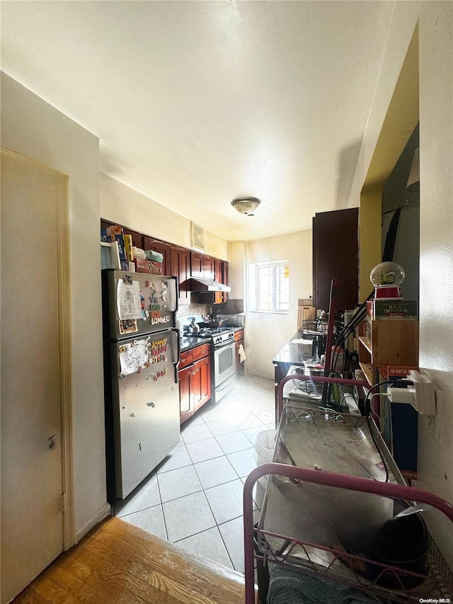 kitchen with light hardwood / wood-style floors, white range with gas stovetop, extractor fan, and stainless steel refrigerator