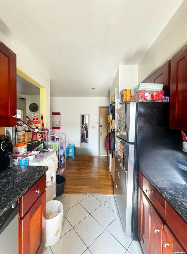 kitchen with dishwasher, light hardwood / wood-style flooring, black refrigerator, and dark stone countertops