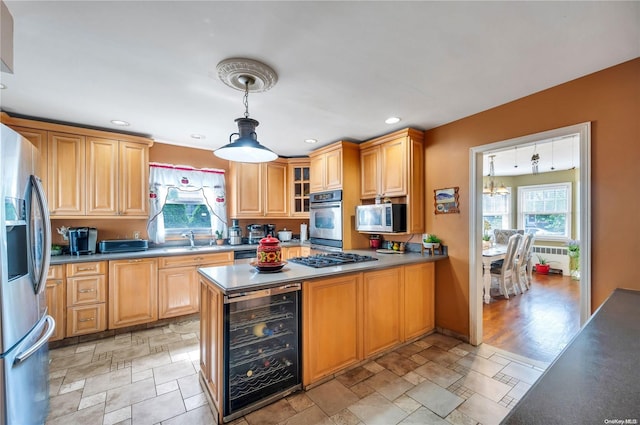 kitchen featuring appliances with stainless steel finishes, light wood-type flooring, sink, decorative light fixtures, and wine cooler