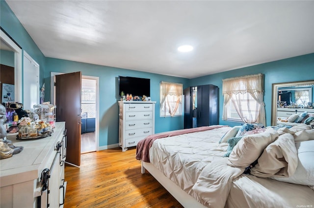 bedroom with multiple windows and light hardwood / wood-style floors