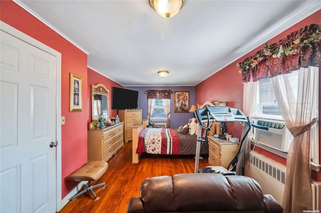 bedroom featuring radiator heating unit, dark hardwood / wood-style floors, multiple windows, and ornamental molding