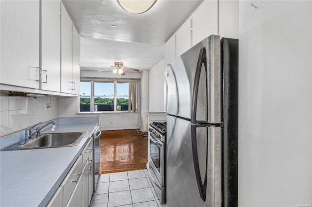 kitchen featuring stainless steel appliances, ceiling fan, sink, white cabinets, and light tile patterned flooring