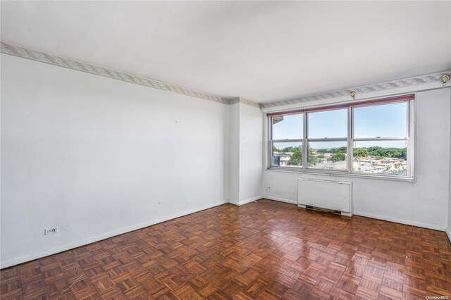 spare room with radiator heating unit and dark parquet floors