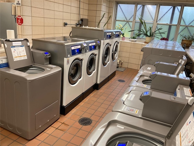 washroom featuring washing machine and dryer, tile walls, and light tile patterned flooring