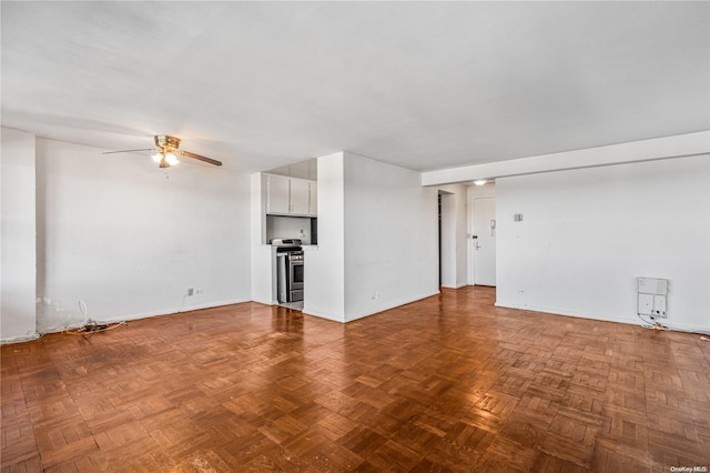 unfurnished living room with a ceiling fan and baseboards