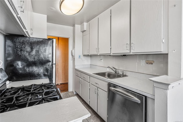 kitchen featuring light countertops, tasteful backsplash, a sink, appliances with stainless steel finishes, and light tile patterned floors