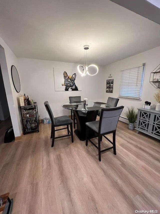 dining room featuring an inviting chandelier, light hardwood / wood-style flooring, and a baseboard radiator