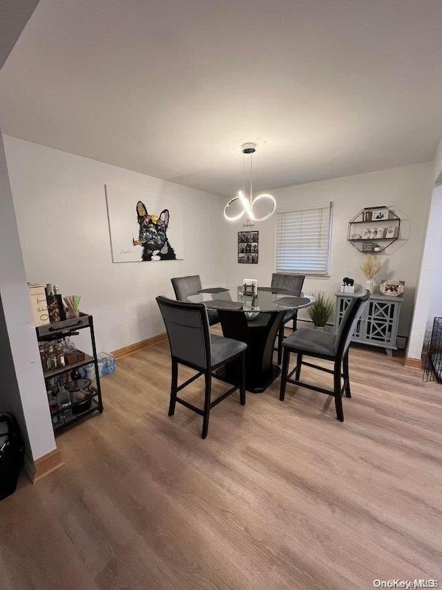 dining space featuring light wood-type flooring and an inviting chandelier