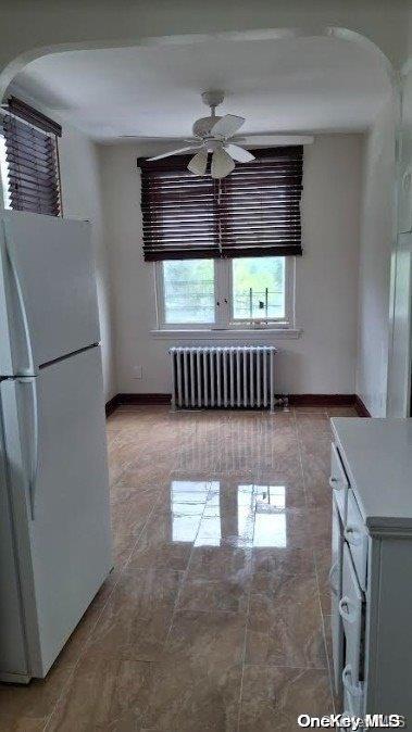 unfurnished dining area featuring radiator and ceiling fan