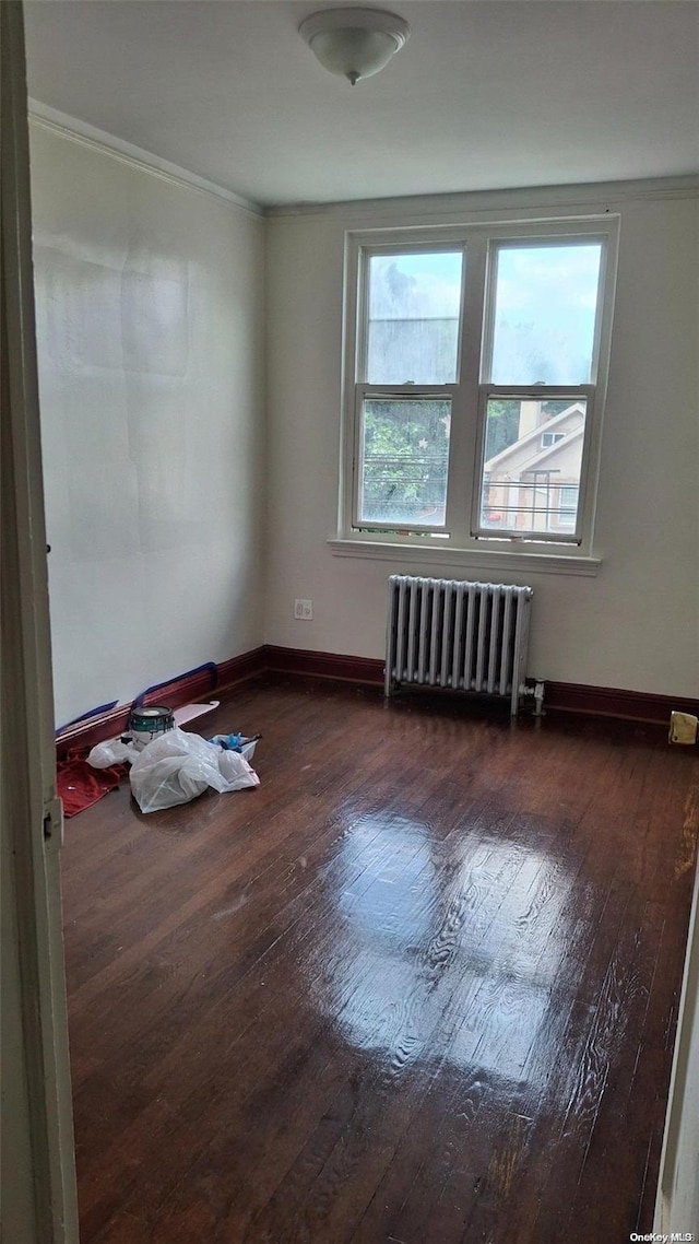 unfurnished room featuring radiator, crown molding, and dark hardwood / wood-style floors