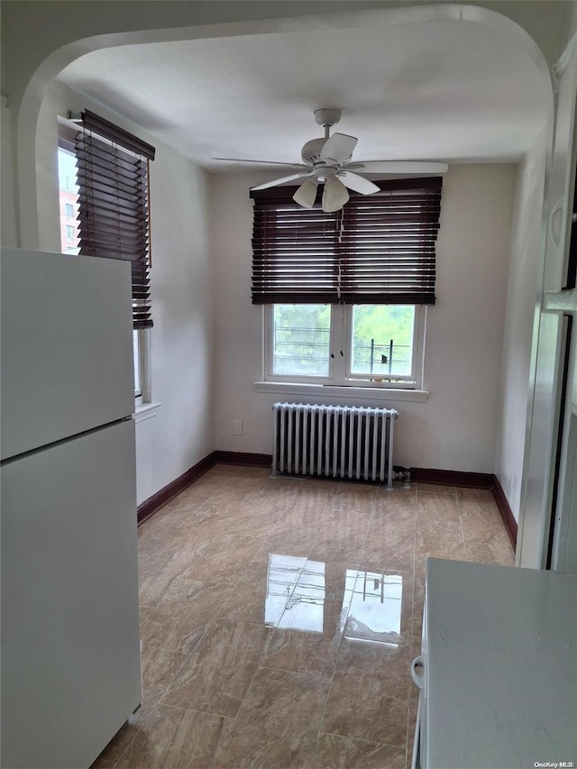 unfurnished dining area featuring radiator heating unit and ceiling fan