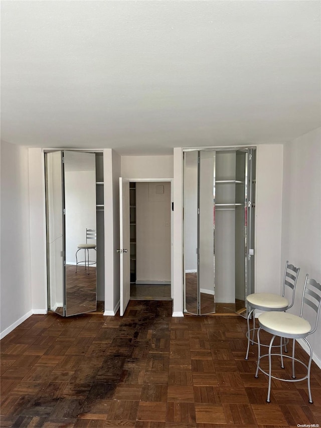 bedroom with dark parquet floors and two closets