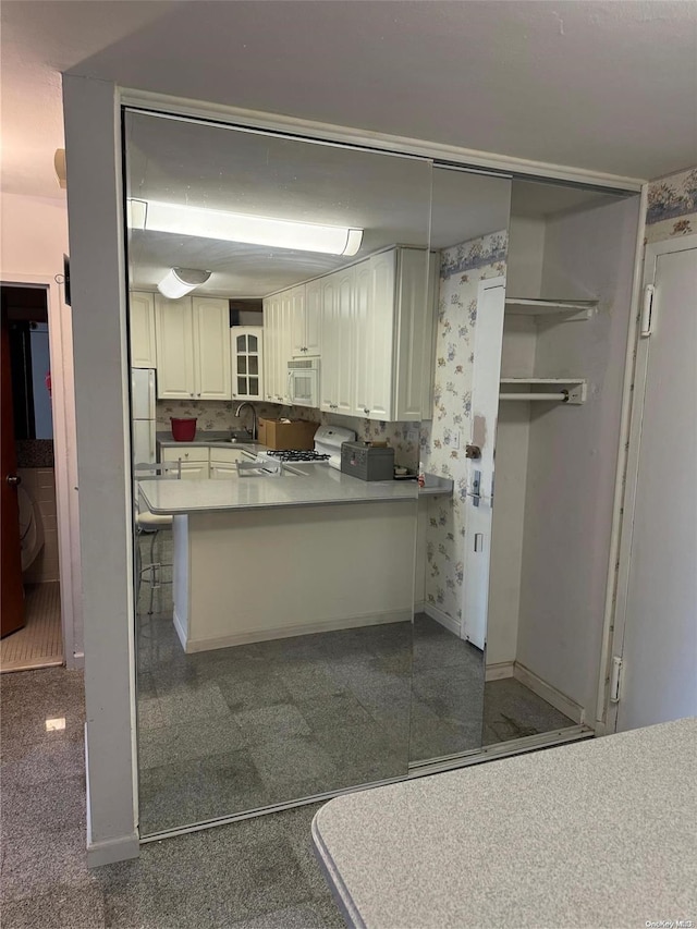 17-85 215th St Unit 4J, Bayside, NY 11360 - kitchen with white microwave, range, baseboards, a peninsula, and a sink