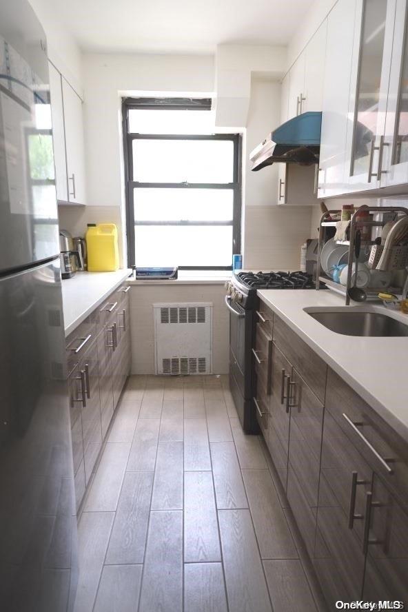 kitchen with sink, white cabinets, light hardwood / wood-style floors, and appliances with stainless steel finishes