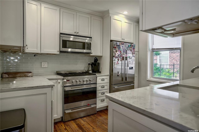 kitchen featuring stainless steel appliances, light stone counters, white cabinetry, and sink