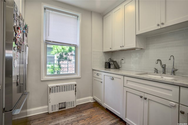 kitchen featuring radiator, stainless steel fridge, sink, and white cabinets