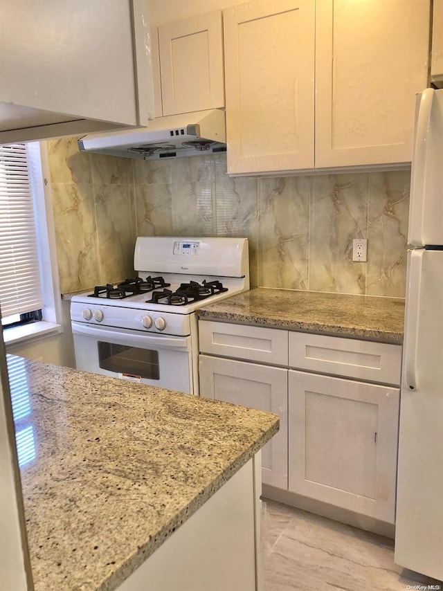 kitchen featuring white appliances, white cabinetry, light stone counters, and tasteful backsplash