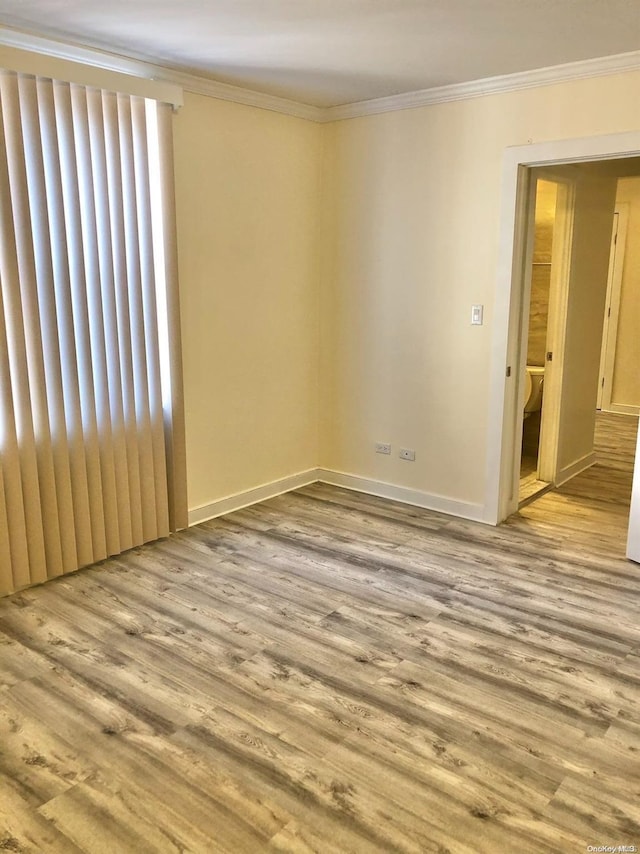 spare room with light wood-type flooring and ornamental molding