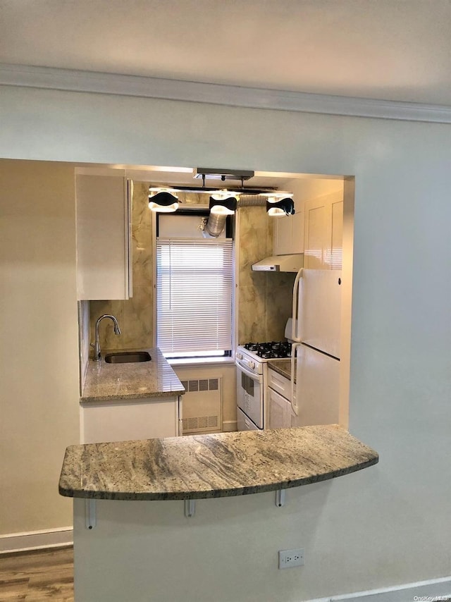 kitchen featuring white appliances, radiator, sink, dark hardwood / wood-style floors, and kitchen peninsula