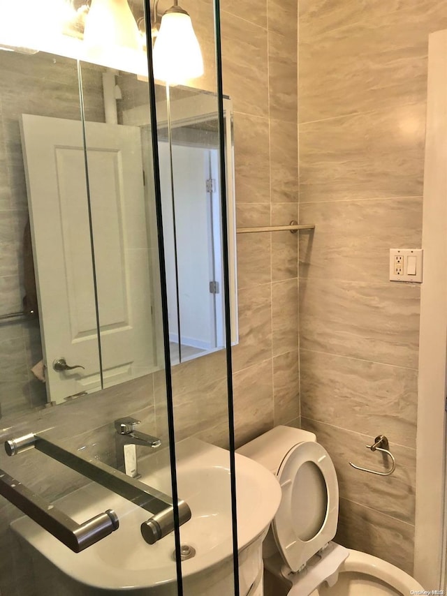 bathroom featuring sink, toilet, and tile walls