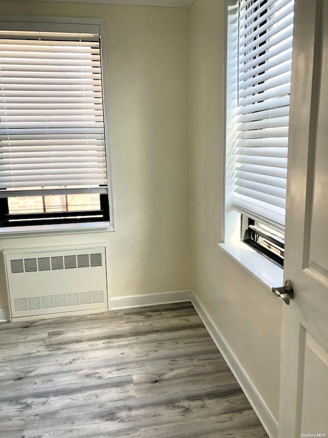 empty room with radiator heating unit, a wealth of natural light, and wood-type flooring