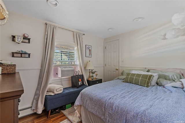 bedroom featuring cooling unit, wood-type flooring, and baseboard heating