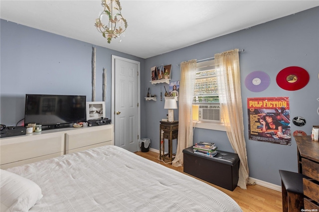 bedroom featuring cooling unit, light wood-type flooring, and an inviting chandelier