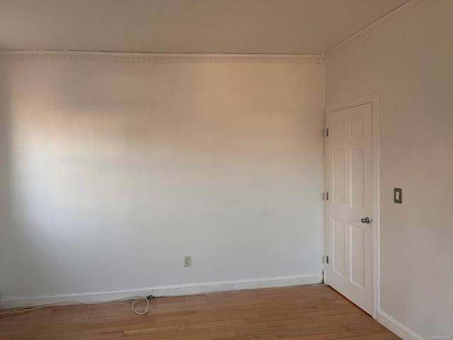 spare room featuring crown molding and light wood-type flooring