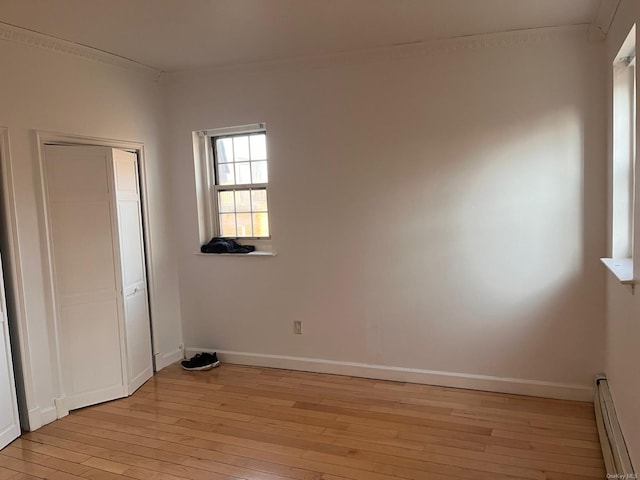 unfurnished bedroom with ornamental molding, light hardwood / wood-style flooring, and a baseboard heating unit