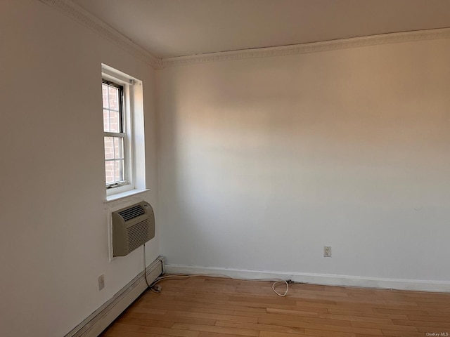 spare room featuring ornamental molding, a wall mounted AC, light hardwood / wood-style flooring, and a baseboard heating unit