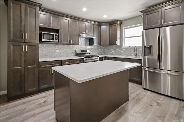 kitchen featuring decorative backsplash, appliances with stainless steel finishes, light wood-type flooring, dark brown cabinetry, and sink