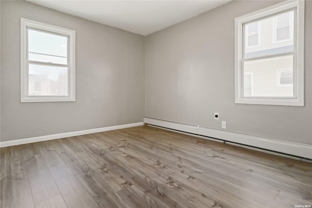 spare room featuring a baseboard radiator and light hardwood / wood-style floors