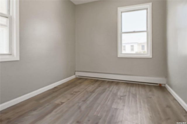 empty room featuring baseboard heating and light hardwood / wood-style floors