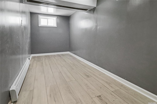 basement featuring light hardwood / wood-style floors and baseboard heating