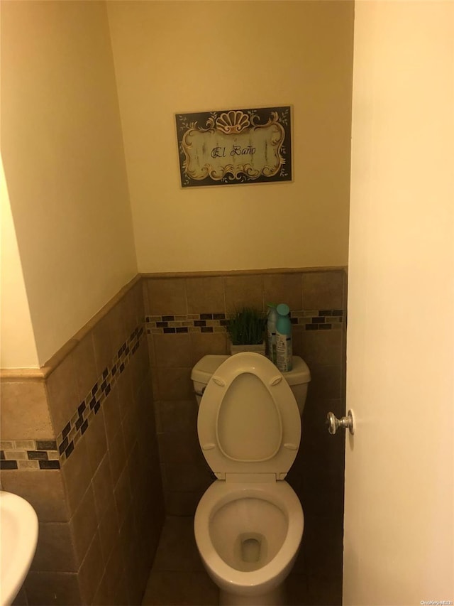 bathroom with tile walls and toilet