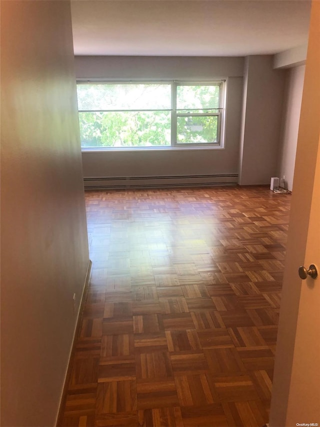 unfurnished room with dark parquet floors and a baseboard radiator