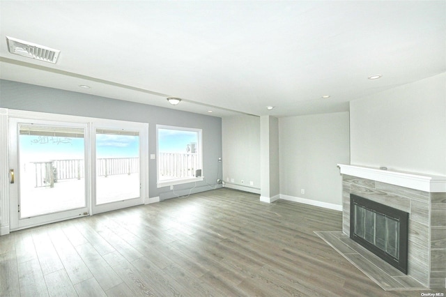 190 Bayview Ave, Lindenhurst, NY 11757 - unfurnished living room with baseboards, wood finished floors, a tiled fireplace, and recessed lighting