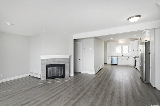 190 Bayview Ave, Lindenhurst, NY 11757 - unfurnished living room featuring baseboard heating, wood finished floors, baseboards, and recessed lighting