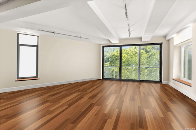 unfurnished room featuring hardwood / wood-style floors, lofted ceiling with beams, a healthy amount of sunlight, and track lighting