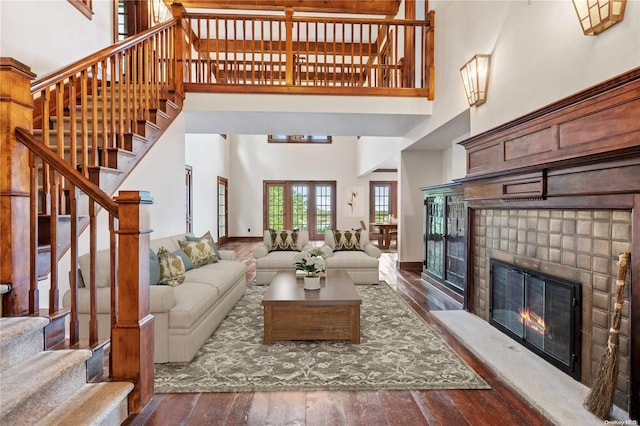 living room with dark wood-type flooring, a high ceiling, and a brick fireplace