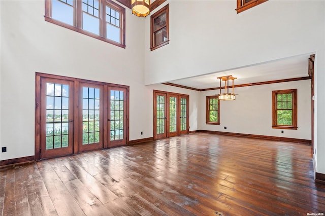 unfurnished living room with dark wood-type flooring, a high ceiling, and ornamental molding