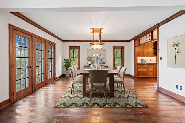 dining area with a healthy amount of sunlight, crown molding, dark wood-type flooring, and french doors