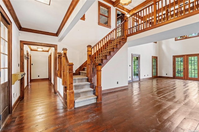 stairs with wood-type flooring, french doors, ornamental molding, and a high ceiling