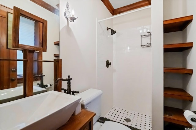 bathroom featuring toilet, a tile shower, ornamental molding, and sink